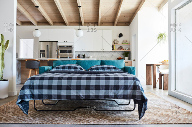 Pullout sofa with blue checkered blanket in modern home