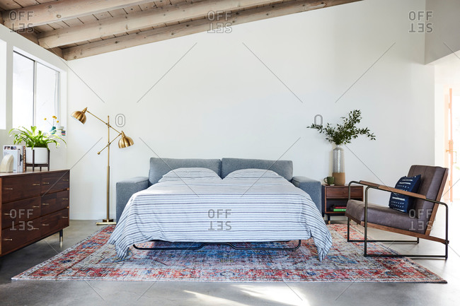 June 1, 2020: Gray pullout sleeper sofa and chair in a living room with exposed beam ceiling