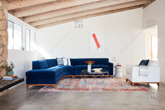 June 1, 2020: Blue velvet sectional sofa in a room with exposed beam ceiling