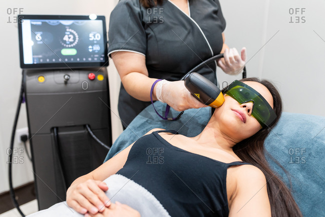 High angle view of woman lying on treatment bed in a beauty salon, receiving facial treatment.