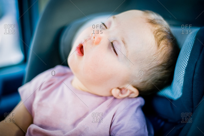 Portrait of baby girl asleep in her car seat.