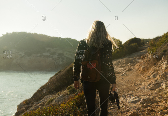 Rear view of woman hiking by the coastline of Catalunya between Sitges and Vilanova I la Geltru, Spain.