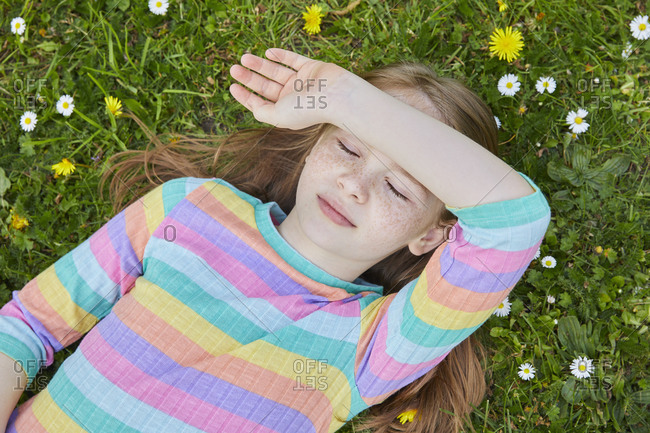 High angle view of girl wearing striped top lying on a spring meadow.