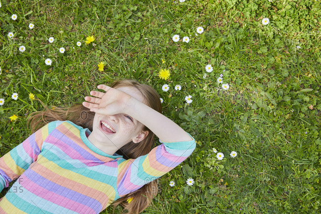 High angle view of girl wearing striped top lying on a spring meadow.