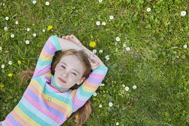 High angle view of girl wearing striped top lying on a spring meadow.