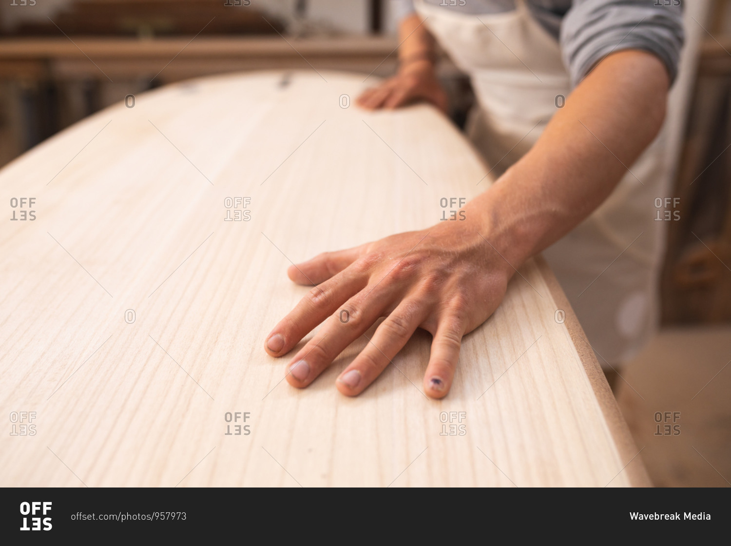 Mid section of a Caucasian male surfboard maker working in his studio, making a surfboard, inspecting it and preparing to polishing..