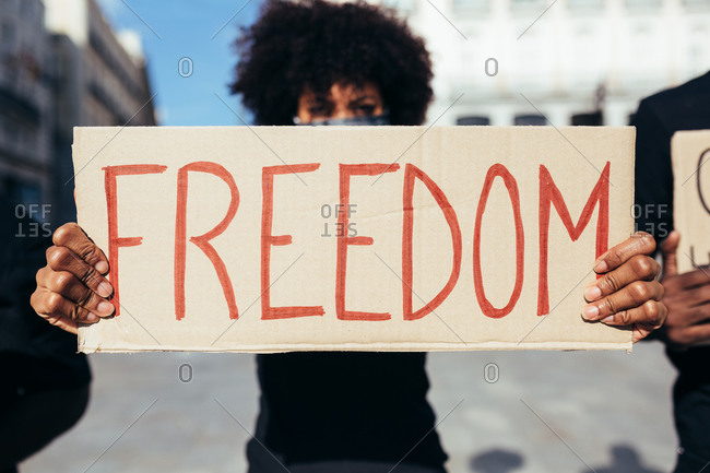 Afro woman protesting at a rally for racial equality holding a "Freedom" poster. Black Lives Matter.