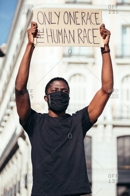 Man crying and protesting at a rally for racial equality holding a poster against racism. Black Lives Matter.