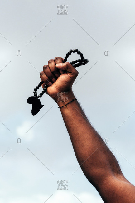 Hand of black anonymous man holding a  pendant in the shape of Africa