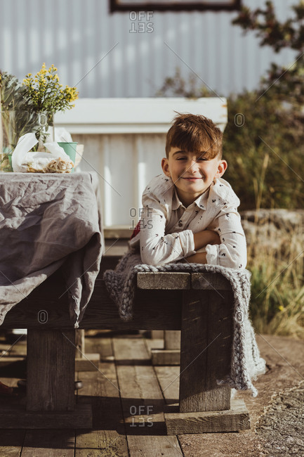 Portrait of smiling boy lying on front over wooden seat