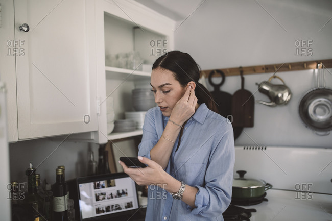 Female design professional wearing in-ear headphones at home office