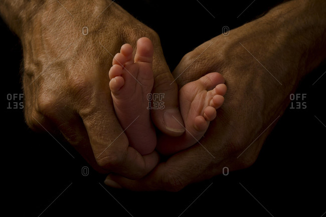 Father's hands holding baby's feet