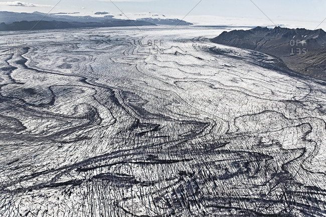 Aerial view, lines and structures consisting of volcanic ash and black lava in the ice and snow of Vatnajoekull glacier, Iceland, Europe