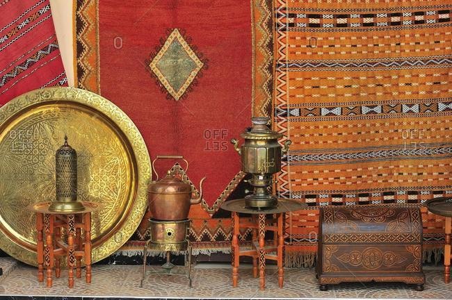 A dealer sells his goods in the souk, bazaar, carpets, brass plates, jugs and chests, Morocco, Africa