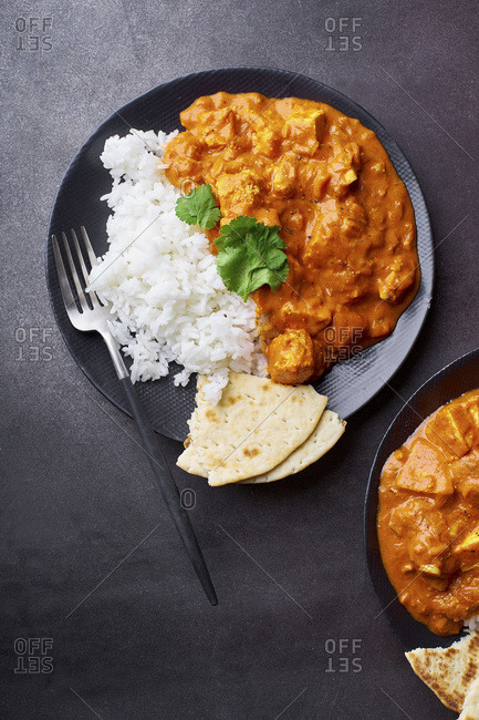 Paneer tikka masala with basmati rice. Indian cuisine, vegetarian dish made of soft cheese cubes cooked in spicy tomato sauce with cream. Top view, dark background.