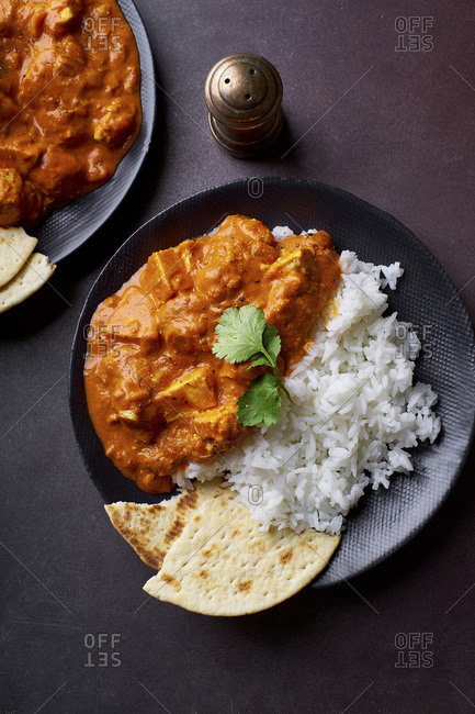 Paneer tikka masala with basmati rice. Indian cuisine, vegetarian dish made of soft cheese cubes cooked in spicy tomato sauce with cream. Top view, dark background.
