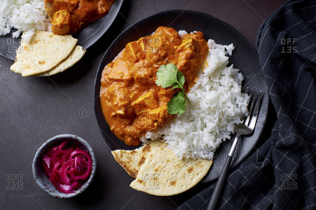 Paneer tikka masala with basmati rice. Indian cuisine, vegetarian dish made of soft cheese cubes cooked in spicy tomato sauce with cream. Top view, dark background.