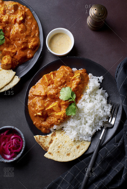 Paneer tikka masala with basmati rice. Indian cuisine, vegetarian dish made of soft cheese cubes cooked in spicy tomato sauce with cream. Top view, dark background.