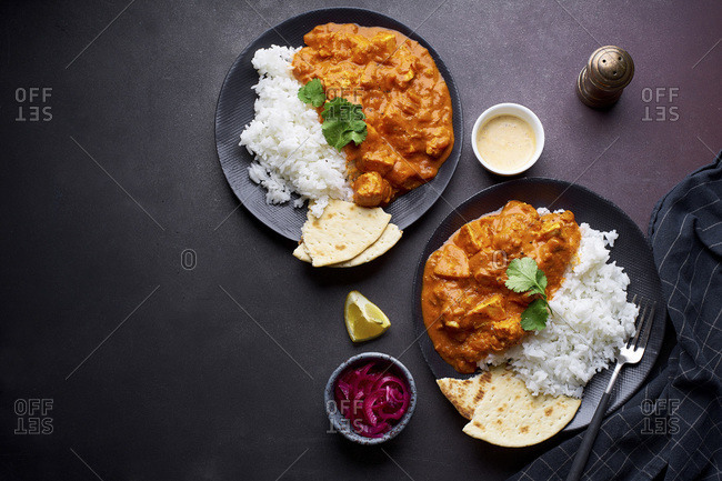 Paneer tikka masala with basmati rice. Indian cuisine, vegetarian dish made of soft cheese cubes cooked in spicy tomato sauce with cream. Top view, dark background.