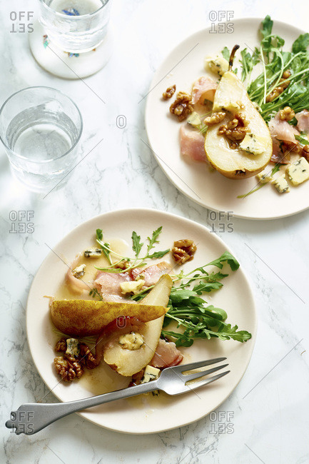 Pear salad with walnuts, prosciutto, arugula and blue cheese. Dinner appetizer on marble table