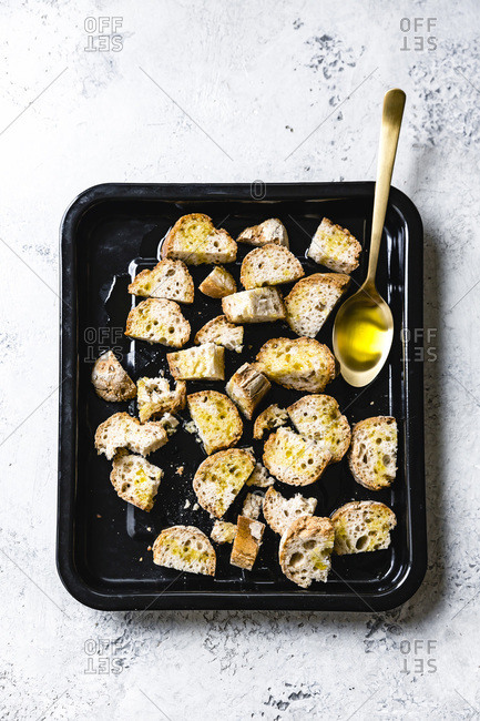 Pieces of bread covered in olive oil on a baking tray.