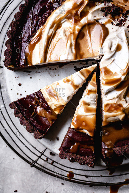 Slices of chocolate caramel tart with whipped coconut cream closeup.