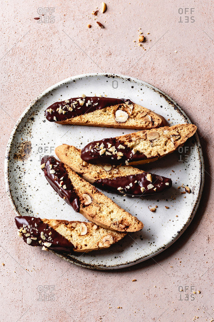 Pieces of chocolate dipped hazelnut biscotti on a ceramic plate.