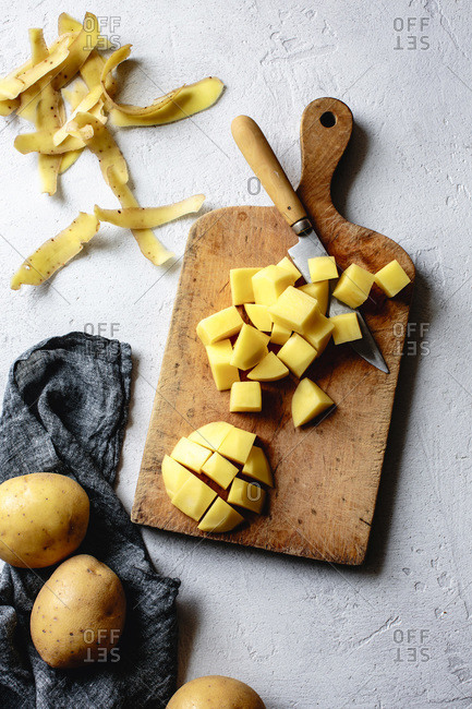 Potatoes diced on a wooden cutting board.
