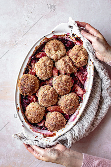 Cranberry and apple cobbler in a hand held baking dish.