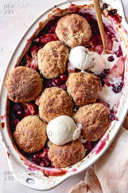 Cranberry and apple cobbler with melting scoops of ice cream.