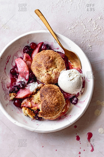 Serving of cranberry apple cobbler with ice cream in a bowl.