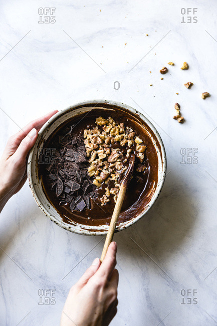 Stirring walnuts and chocolate into brownie batter.