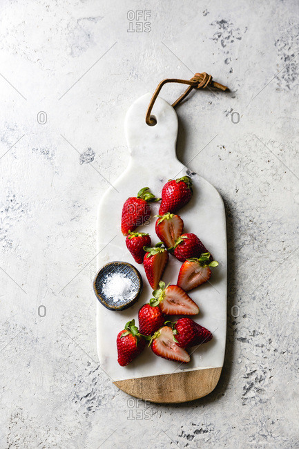 Strawberries and salt on a marble cutting board.
