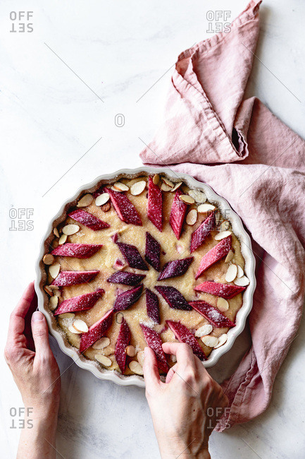 Pieces of rhubarb placed on cake batter by a hand.