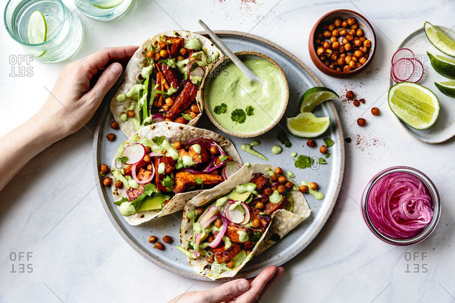 Sweet potato chickpea tacos with cilantro crema on a hand held plate.