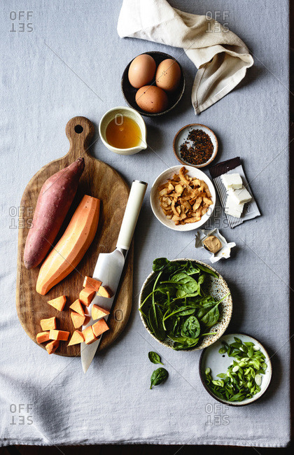 Sweet potato, spinach, scallions, coconut and eggs on a table.