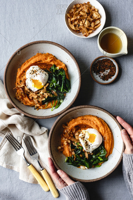Hands holding a sweet potato breakfast bowl.