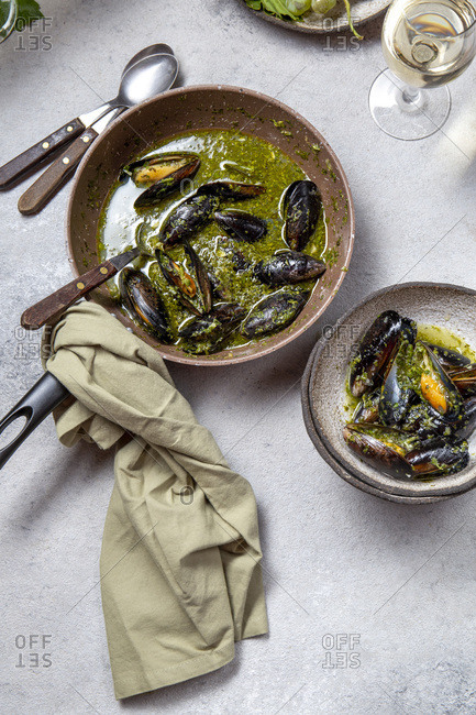 Mediterranean style dinner. Flat-lay of table with Mussels in green sauce and white wine, top view.