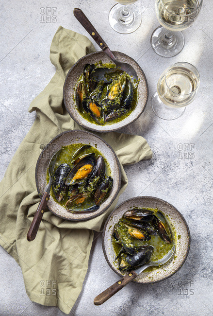 Mediterranean style dinner. Flat-lay of table with Mussels in green sauce and white wine, top view.