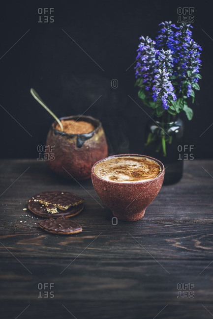 Cup of coffee and chocolate cookies on a rustic wooden table
