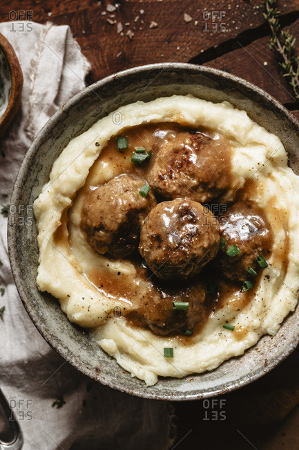 A bowl with mashed potatoes and meatballs