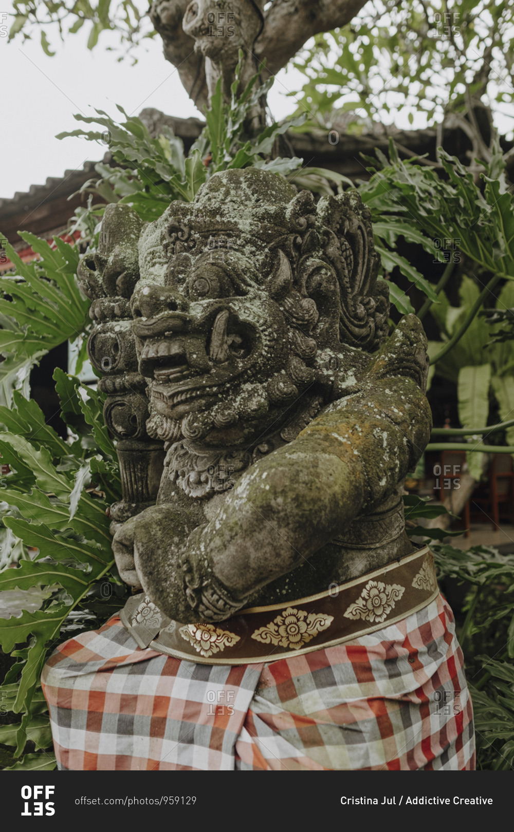 Low angle of statue of Demon surrounded by green tropical foliage in Bali