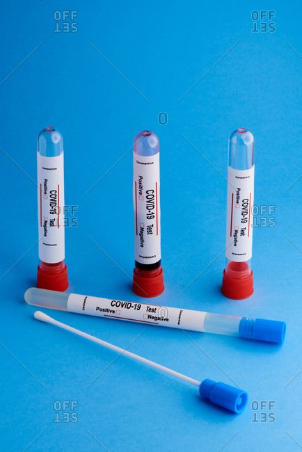Test tubes with blood samples and cotton swabs for nasal or saliva swab used for COVID 19 diagnostic on blue background