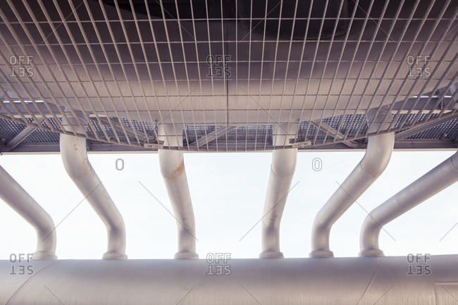 From below of row of metal pipes of air conditioning system placed outdoors of industrial complex