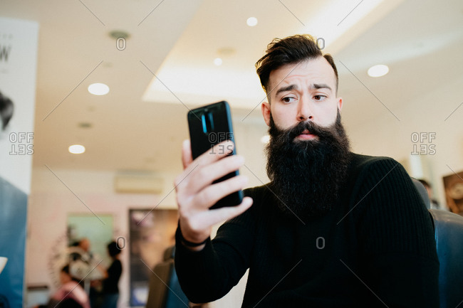 Bearded man taking selfie in barber shop