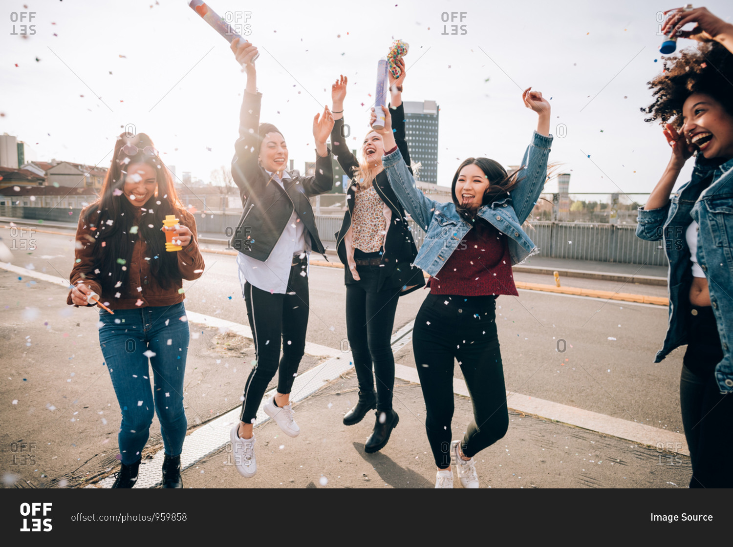 Friends celebrating with confetti and soap bubbles in street, Milan, Italy