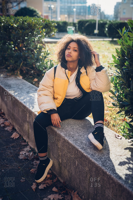 Cool young woman sitting on urban wall, portrait
