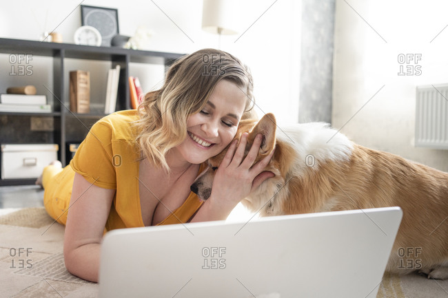 Woman with dog using laptop in living room at home