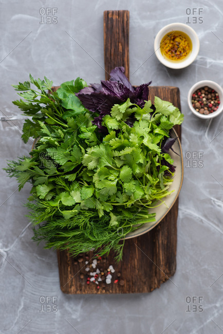 Green fresh herbs on wooden cutting board. Red basil, cilantro, parsley, dill