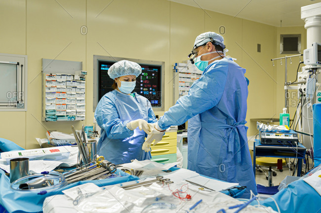Nurse helping doctor put on gloves for surgery in a hospital operating room